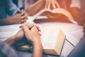 Christians are congregants join hands to pray and seek the blessings of God, the Holy Bible. They were reading the Bible and sharing the gospel with copy space.