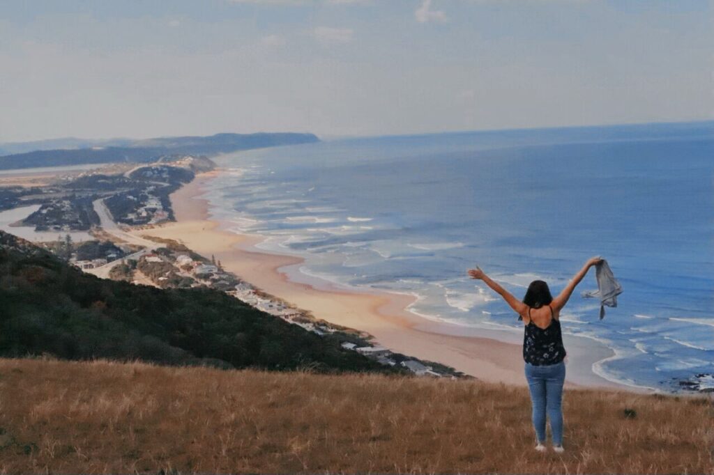 Girl watching over the ocean with arms stretched out